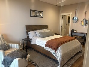 A bedroom with a bed, bedside tables, a chair, and a mirror on the wall. - New Listing: Modern Mountain Farmhouse with Views (Union Mills)