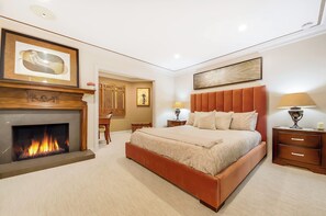 A bedroom with a fireplace, a bed with a headboard, bedside tables, and artwork on the walls. - Encinitas by the Beach - Outdoor Delight (Encinitas)