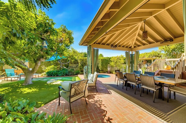 A covered outdoor patio with a pool, seating area, and lush greenery. - Encinitas by the Beach - Outdoor Delight (Encinitas)