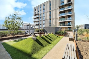 A modern building with multiple balconies and a well-maintained rooftop garden with grass, seating, and trees. - Modern London Apartment Near The O2, ExCeL & London City Airport - Sleeps 5 (London)