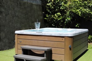 A hot tub with a glass on it, a bench, and a wall in the background. - Villa Infini Blue—A Family Getaway with a Pool, Hot Tub, Pool Table, and Kids' Games (Les Trois-Îlets)