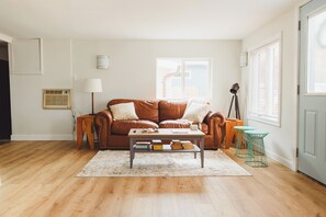 A living room with a brown leather sofa, a coffee table, and a small wooden side table. - The Huron House - Lake Access (Brights Grove)