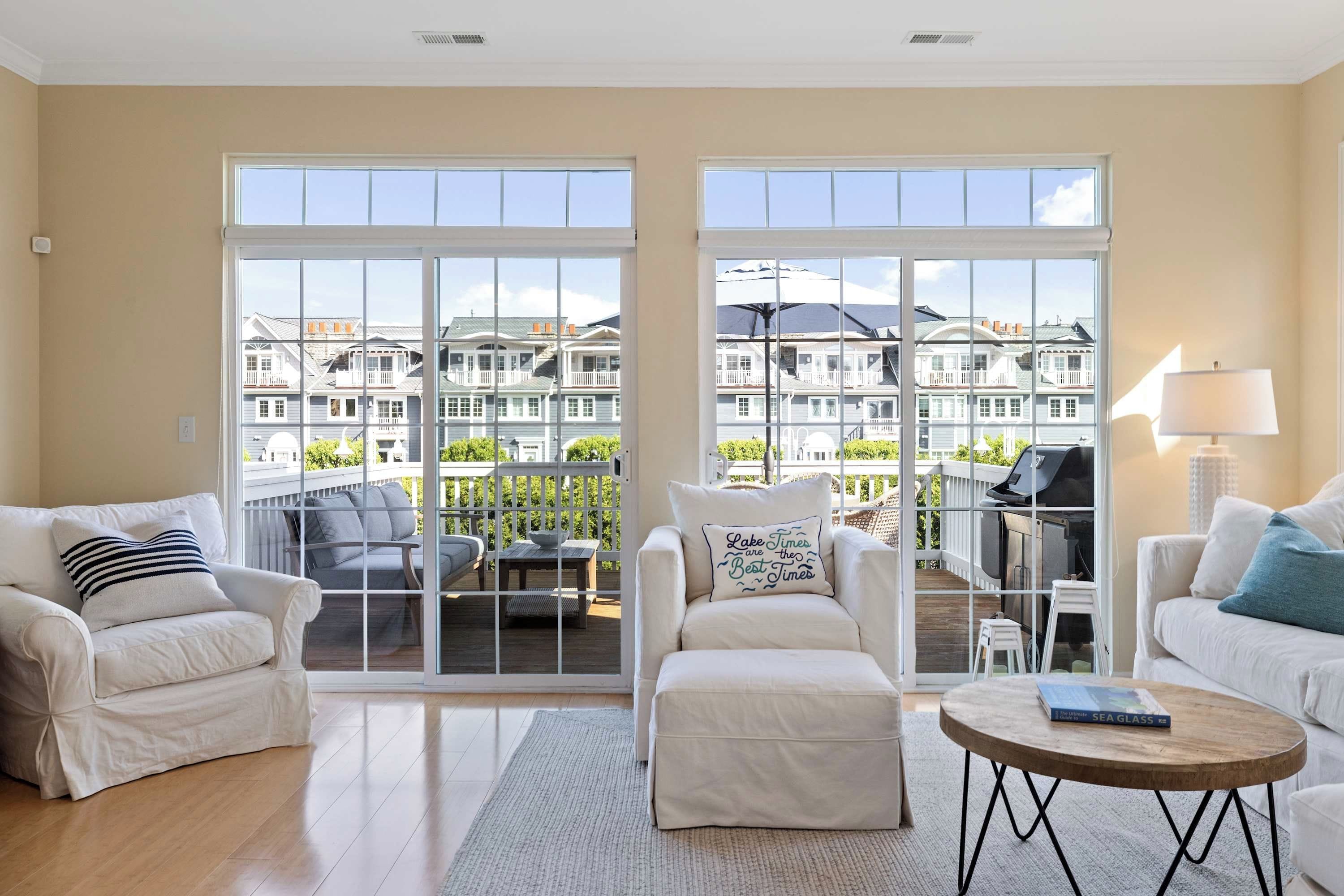 A spacious living room with a large sliding glass door leading to a deck, a fireplace, and a view of a residential area.