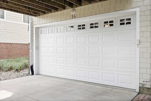 A white garage door with a number '14' above it, a brick wall, and a concrete driveway. - Rooftop Sunsets, EV Charger, Pool & Steps to Beach (New Buffalo)