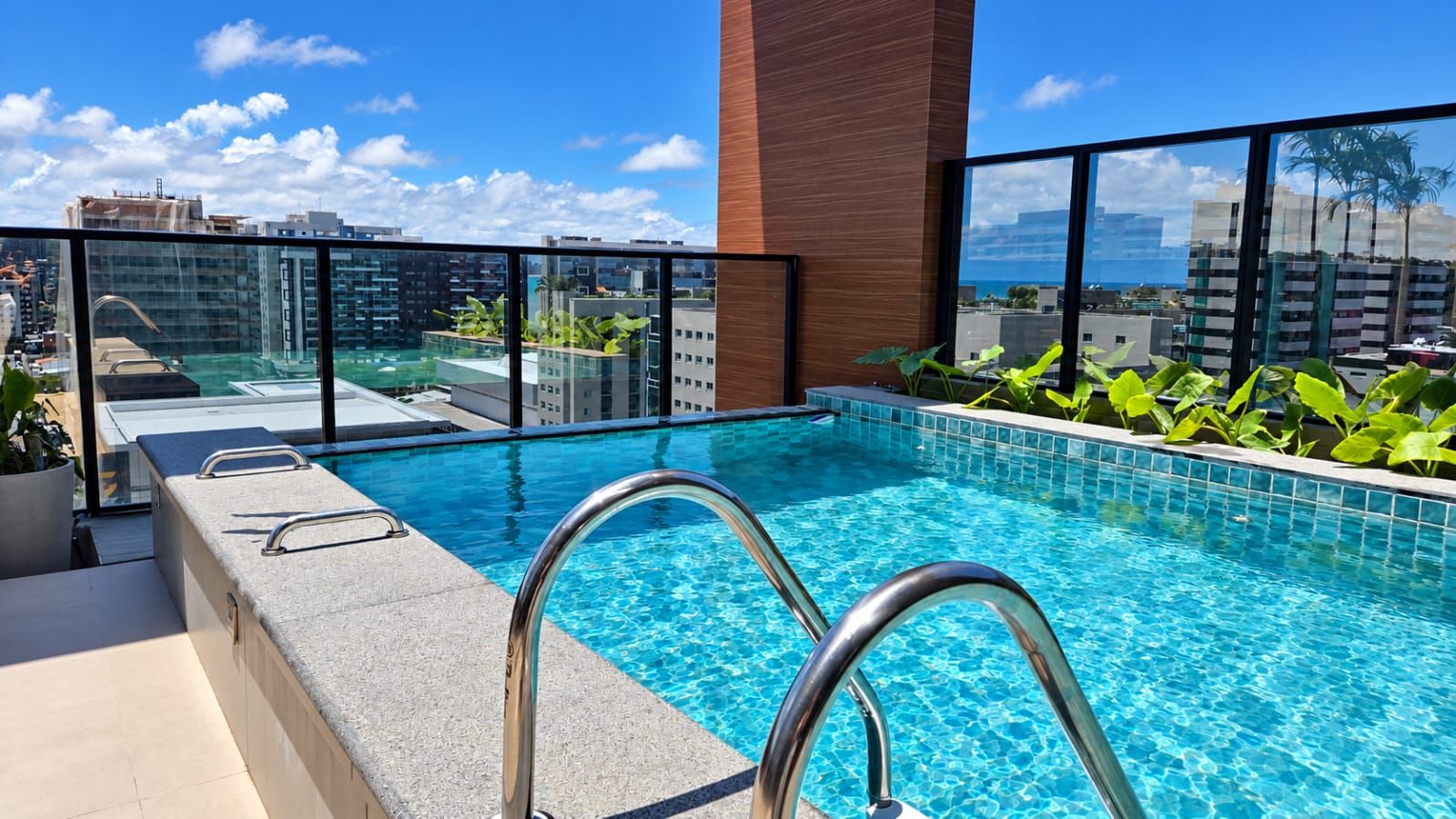 A rooftop swimming pool with clear blue water, surrounded by a modern building with large windows.