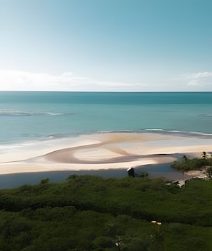 Eine Küstenlandschaft mit Strand, Vegetation und einer Struktur in der Ferne.