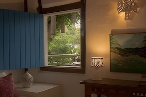 Una habitación con ventana, lámpara y un cuadro.