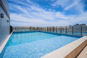 A rooftop swimming pool with a glass barrier, surrounded by a cityscape. - Studio in Condo. w/ Pool 760m to Beach Smt0212 (Salvador)