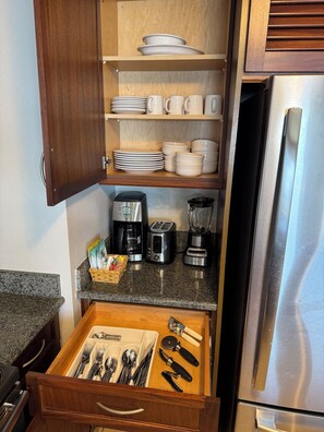 A kitchen with wooden cabinets, a stainless steel refrigerator, a coffee maker, a toaster, and a blender on the countertop. - Kaanapali Beach Maui  3-bedroom condo, ocean front walk out Lanai. 4 large pools (Lahaina)