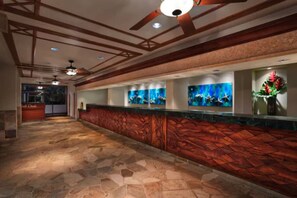 A reception area with a stone floor, wooden paneling, and ceiling fans. - Kaanapali Beach Maui  3-bedroom condo, ocean front walk out Lanai. 4 large pools (Lahaina)