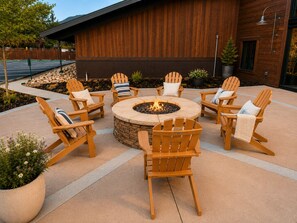 A circular outdoor seating area with a fire pit, surrounded by wooden Adirondack chairs with cushions, in front of a wooden building. - Romantic Retreat - 4 Min to Skiing (Park City)