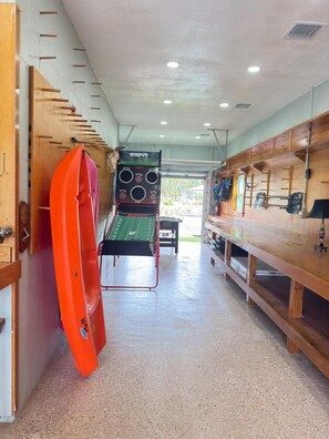 Ein Zimmer mit einer hölzernen Sitzbank, einem Surfbrett und einer Wandlautsprechersanlage.