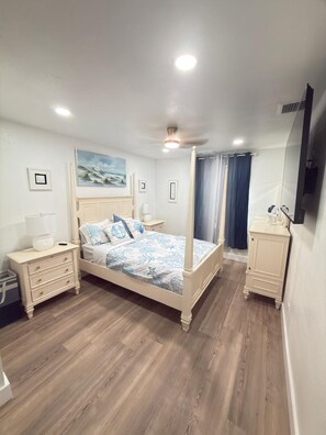 Ein Schlafzimmer mit einem Himmelbett, Nachttischen, einem Schminktisch und einem Deckenventilator.