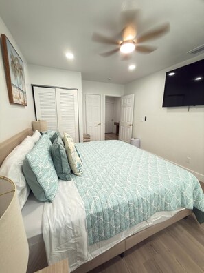 A bedroom with a bed, ceiling fan, and a TV mounted on the wall. - Perfect 6-bedroom house with AC in charming Hudson (Hudson)