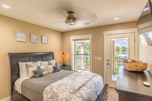 A bedroom with a bed, bedside lamp, and a view of the outdoors through a door. - Waterfront Home with Pool-Dock-Waterviews-Near the Beach (Panama City Beach)