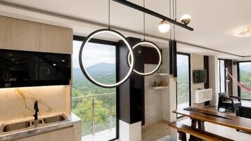 A modern kitchen with a marble floor, pendant lighting, and a view through large windows.