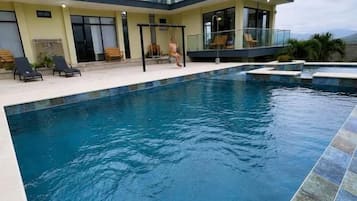 Edifici modern amb piscina, espais d'estar a l'aire lliure i vista despejada del cel.