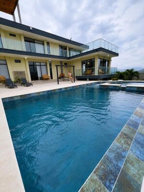 A modern building with a swimming pool, outdoor seating, and a clear view of the sky. - CABAÑA SANDY HOUSE BY MJS (Santa Marta)