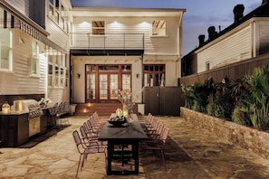 A patio with a dining table and chairs, an outdoor grill, and a brick wall. - 9BR Historic Inn | Pool, Sauna & Outdoor Theater (New Orleans)