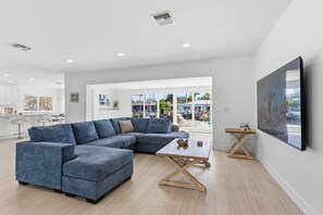 A modern living room with a sectional sofa, a coffee table, and a TV mounted on the wall. - Pompano Waterfront | Heated Pool, 50' Dock, Pets (Pompano Beach)