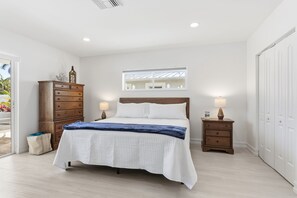 A bedroom with a bed, two bedside tables, a dresser, and a window. - Pompano Waterfront | Heated Pool, 50' Dock, Pets (Pompano Beach)