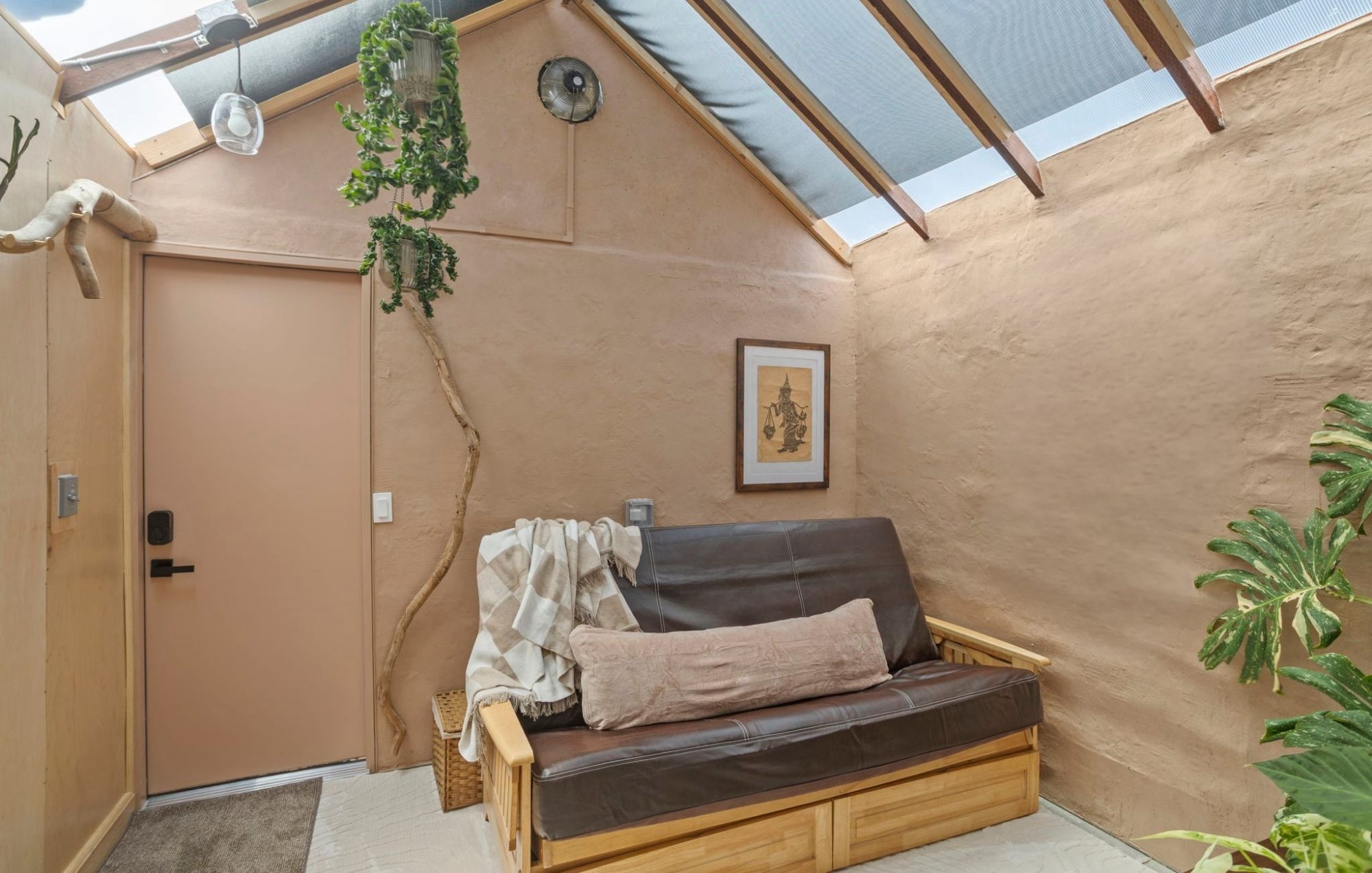Una habitación acogedora con un banco de madera, un cuadro enmarcado en la pared y una planta grande.