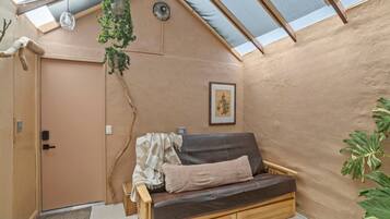 Una habitación acogedora con un banco de madera, un cuadro enmarcado en la pared y una planta grande.