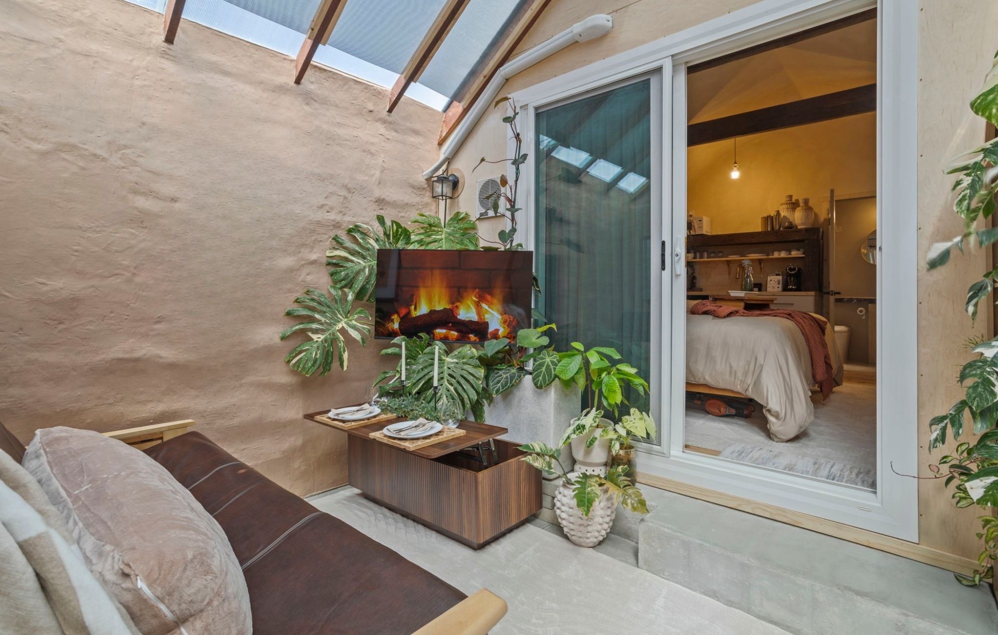 Un espace extérieur accueillant, aménagé avec un foyer, une table à manger et diverses plantes.