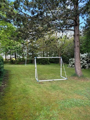 A grassy area with a metal swing set and a tree. - Renovated old school from 1927 close to the sea (Ulfborg)