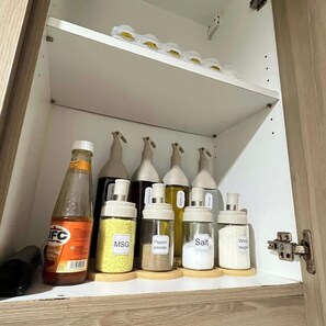 Un meuble de cuisine contenant divers condiments et une bouteille de sauce.