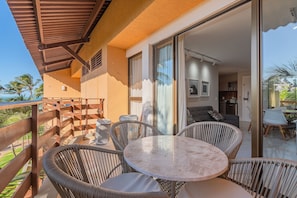 Een balkon met rieten meubilair en een glazen deur naar een binnenruimte.