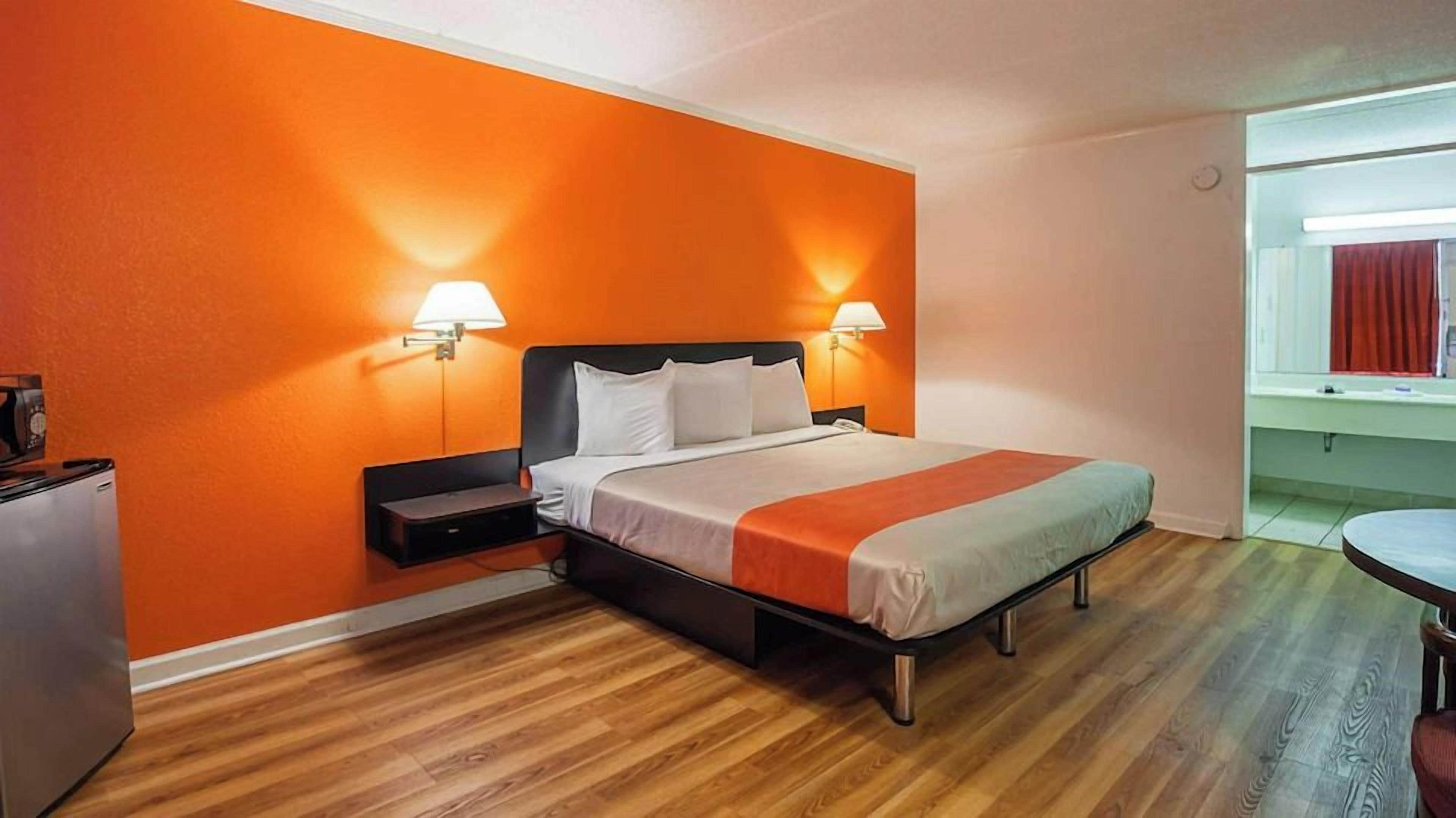 Una habitación de hotel con una cama, lámparas de noche, un escritorio y una mesita.