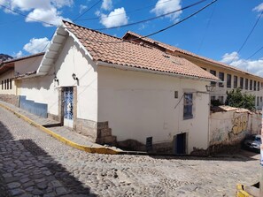 A building with a tiled roof, a stone staircase, and a cobblestone street. - Casa Waynapata Centro Histórico Cusco (Cusco)