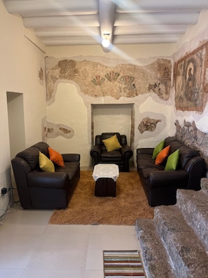 Una sala de estar con dos sofás de cuero negro, una mesita blanca y una alfombra de pelo corto color café.