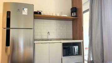 Een kleine keuken met een koelkast, magnetron en koffiezetapparaat.