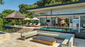 A modern house with a swimming pool, outdoor seating, and a dining area. - Casa Ombak 7-Bedroom Luxury Villa with Spa & Ocean View (Puntarenas Province)