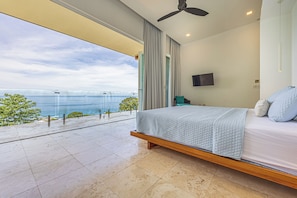 Ein Schlafzimmer mit Bett, Fernseher und Meerblick.