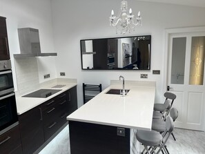 Een moderne keuken met een centraal eiland, een inbouwoven en een grote spiegel boven de gootsteen.