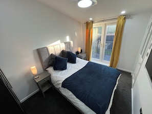 Een hotelkamer met een bed, nachtkastjes, een lamp en uitzicht op de omgeving.