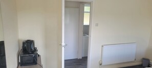 Een kamer met een witte radiator, een gesloten deur en een koffieapparaat op een standaard.