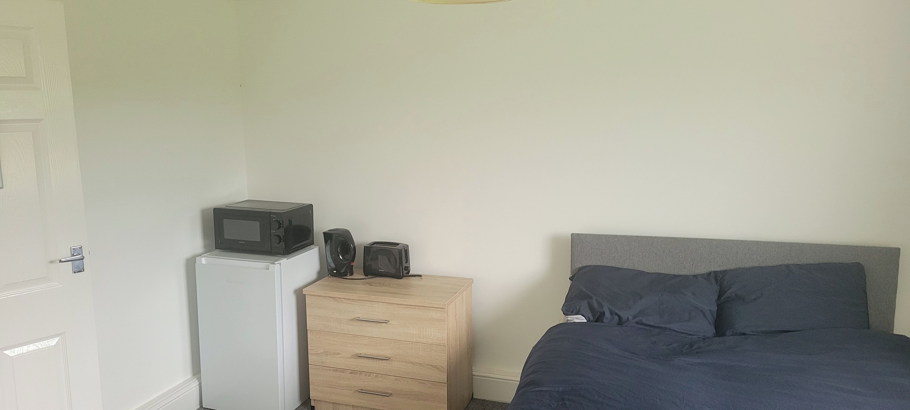 Un dormitorio con cama, cómoda, microondas y tostadora.