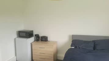 A bedroom with a bed, a dresser, a microwave, and a toaster.