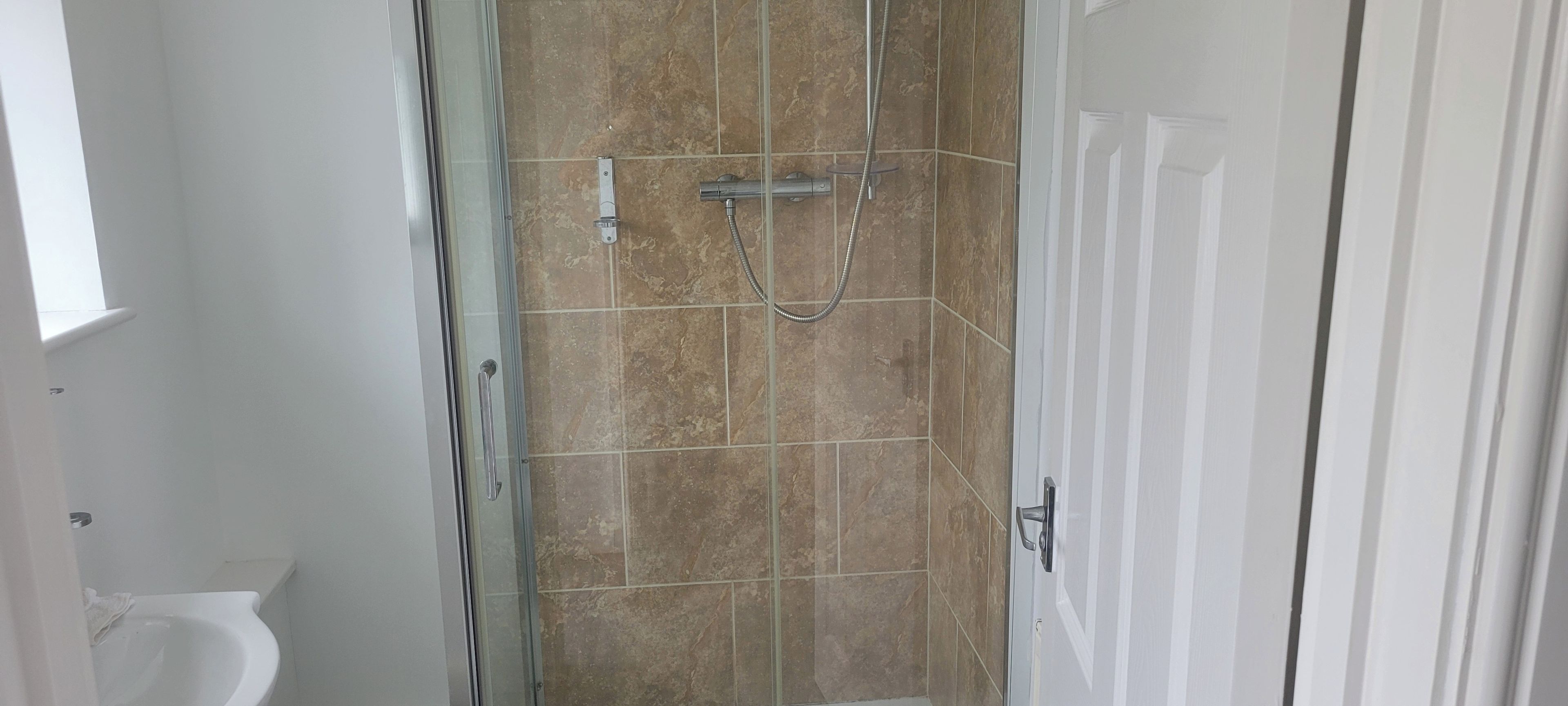 Een badkamer met een douche, toilet en deur.