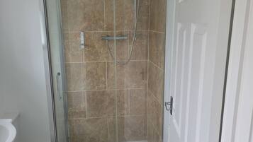 Een badkamer met een douche, toilet en deur.
