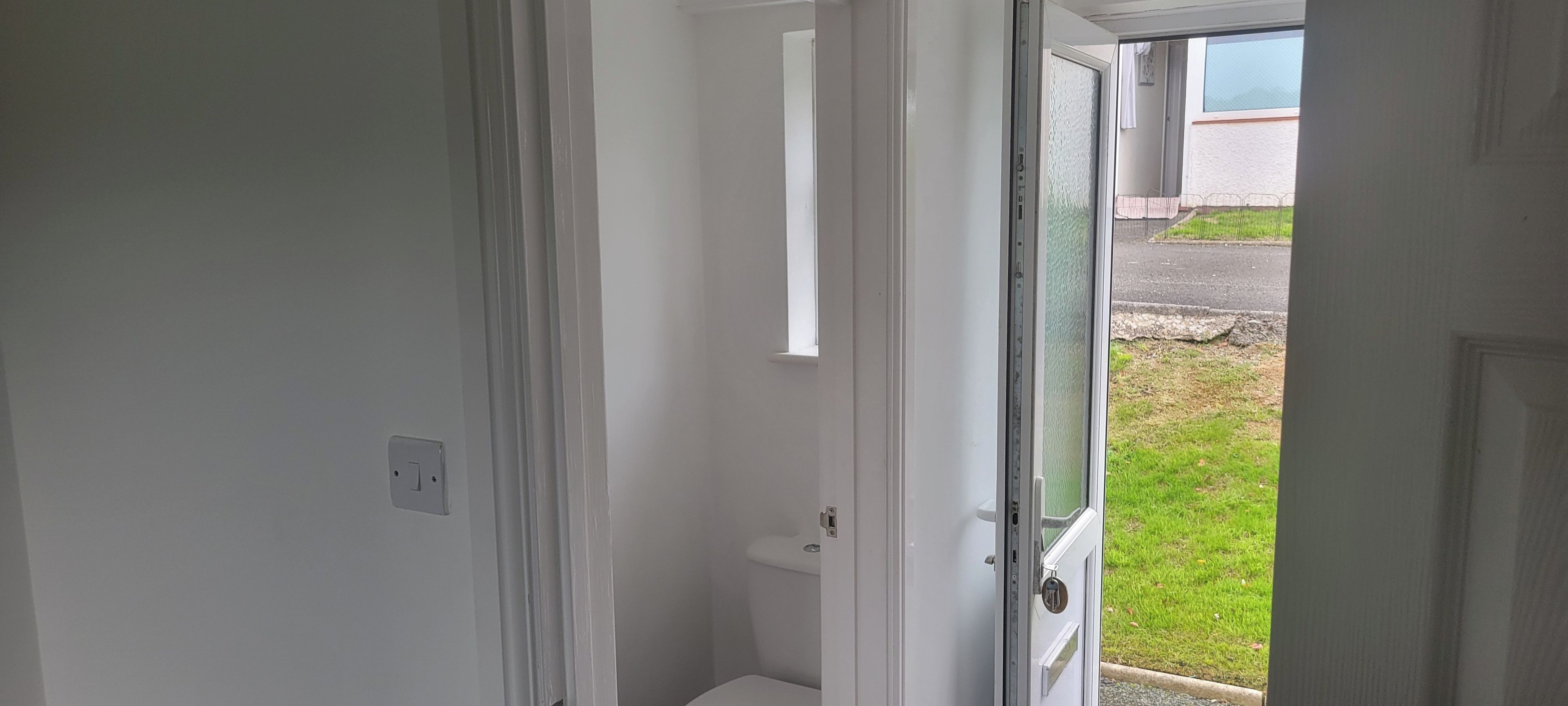 Een deuropening naar een kleine, afgesloten ruimte, toilet zichtbaar.