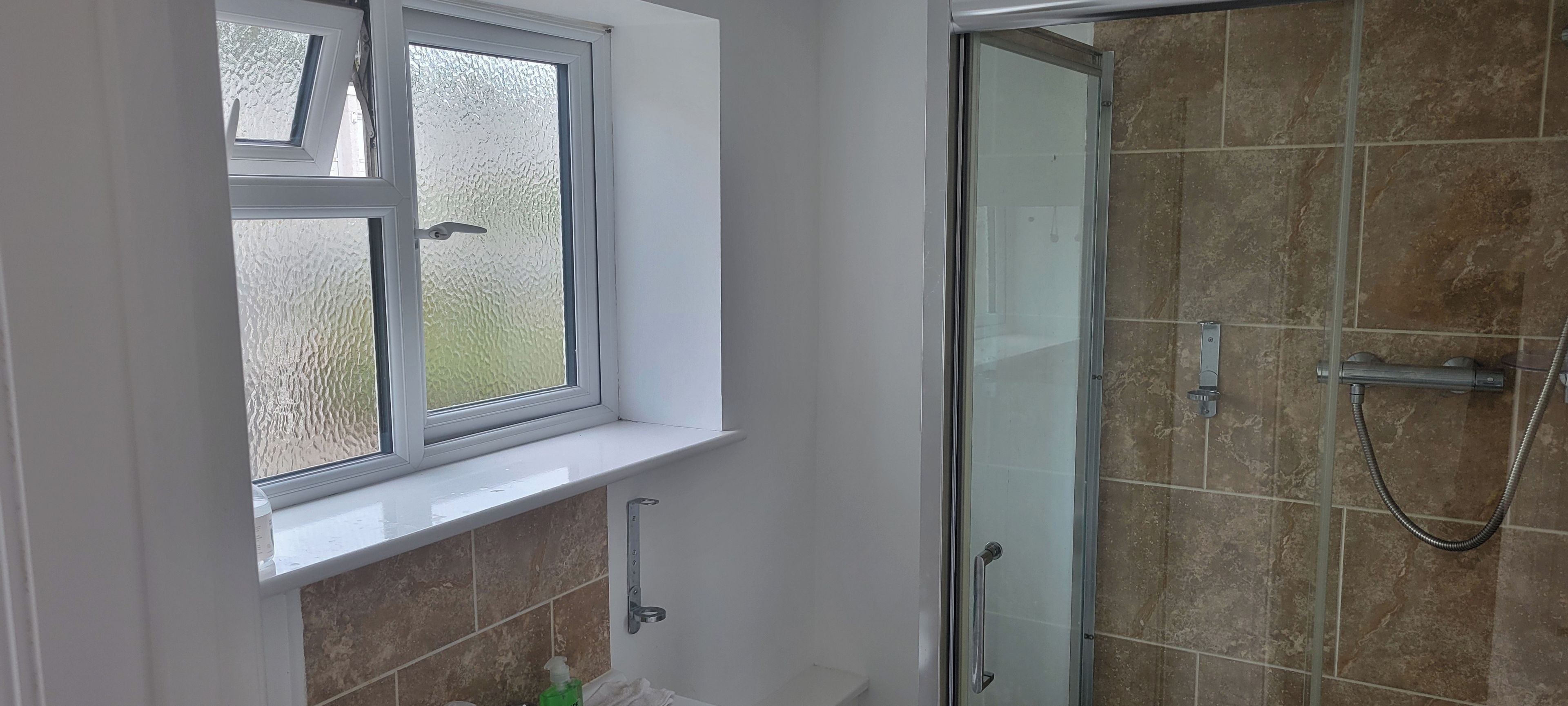 Un bagno con doccia, una finestra e un porta asciugamani.