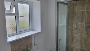 Un bagno con doccia, una finestra e un porta asciugamani.