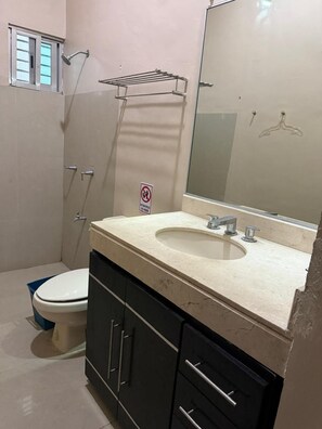 A bathroom with a toilet, sink, mirror, and shower. - Departamentos Gonzalo Guerrero (Mérida)