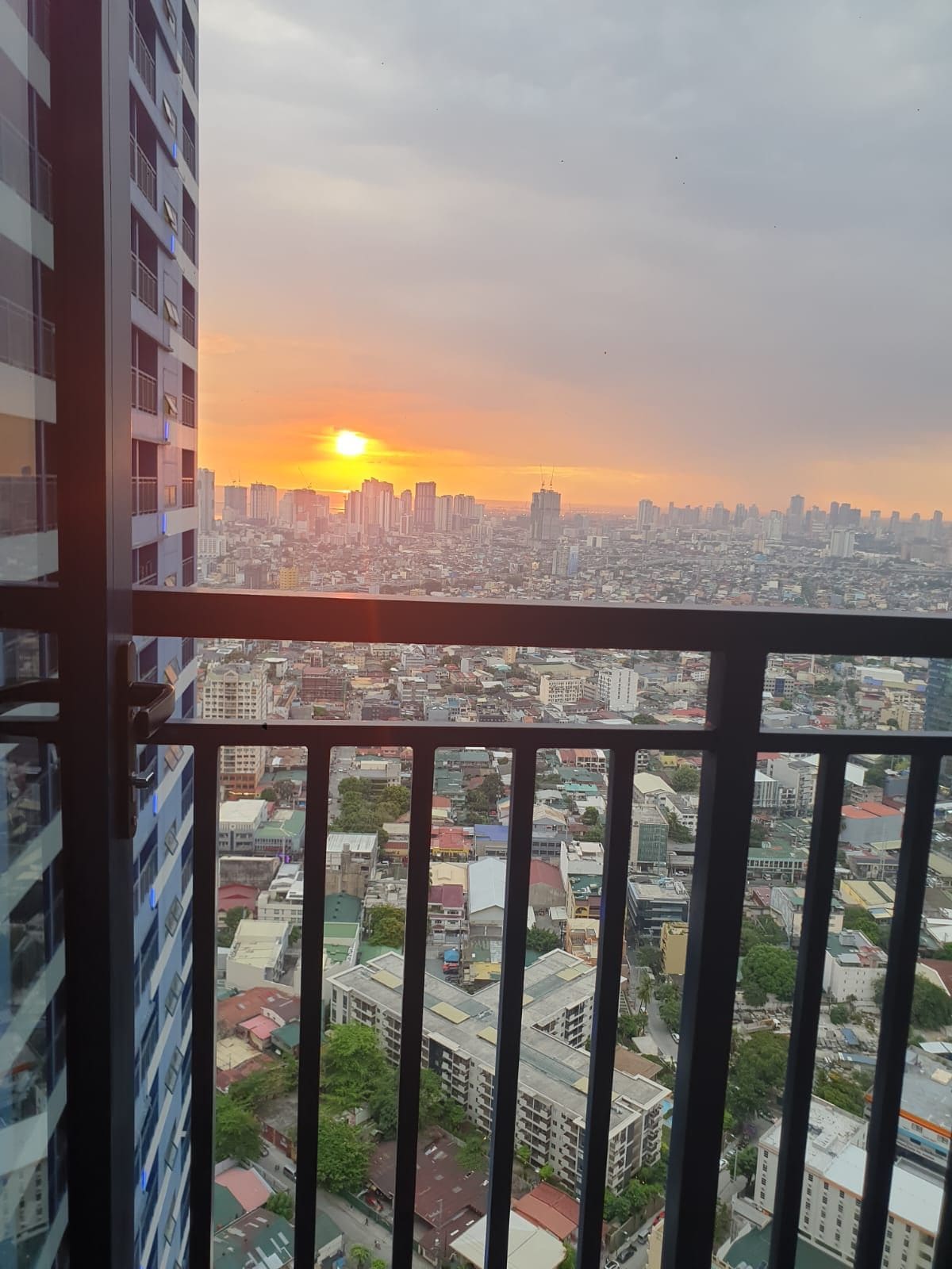 Un edificio alto con balcón que ofrece vistas a una ciudad al atardecer.