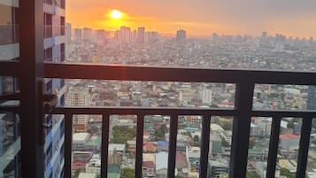Un edificio alto con balcón que ofrece vistas a una ciudad al atardecer.
